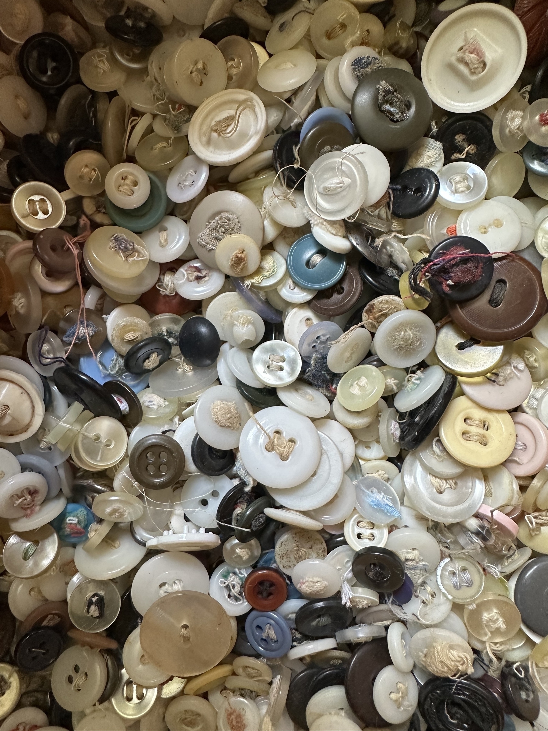 A diverse collection of assorted buttons in various colors, shapes, and sizes is scattered.