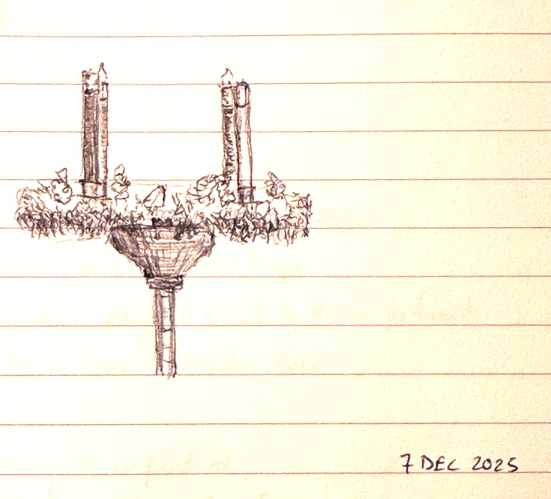 A detailed sketch of a candelabrum with two candles surrounded by ornate decorations is drawn on lined paper.