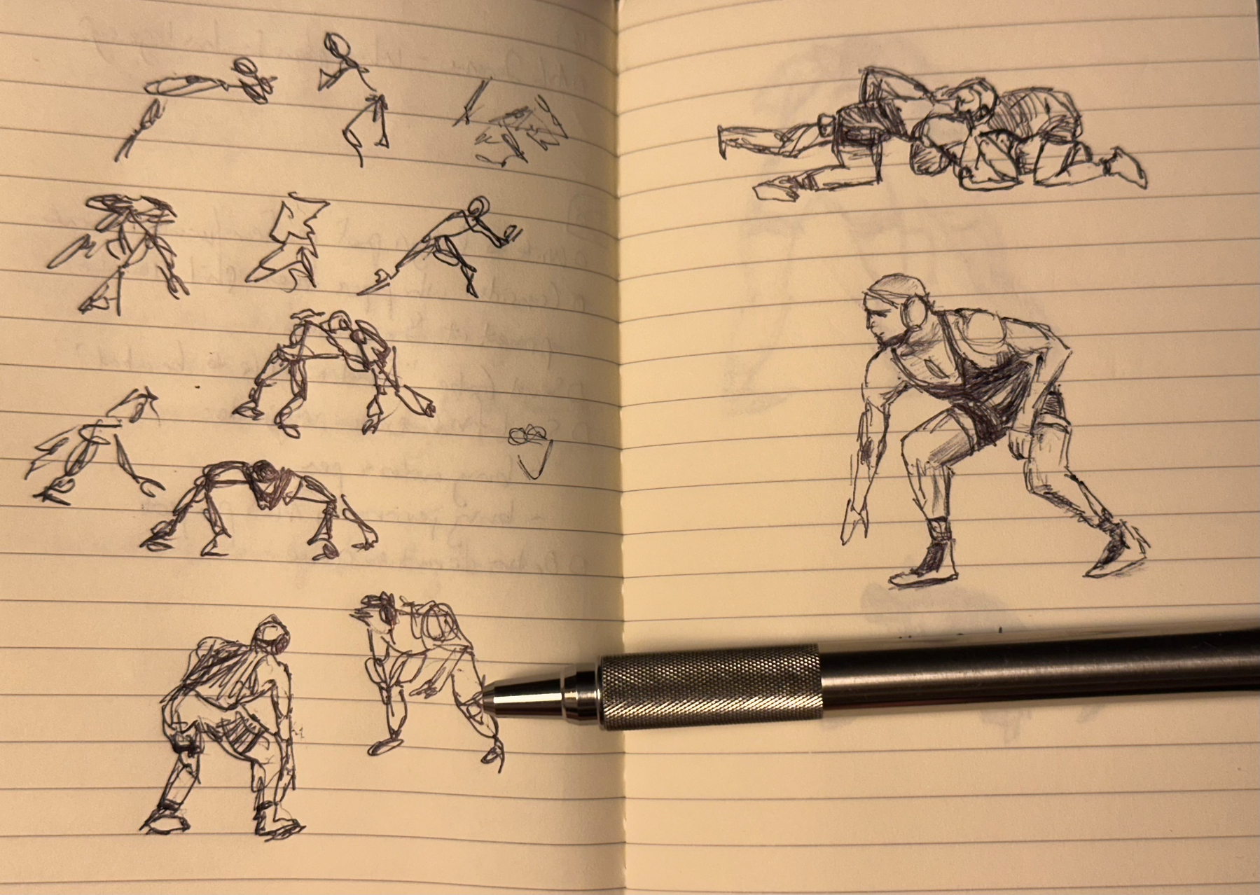 A notebook showcases several sketches of wrestlers in various poses alongside a pen.