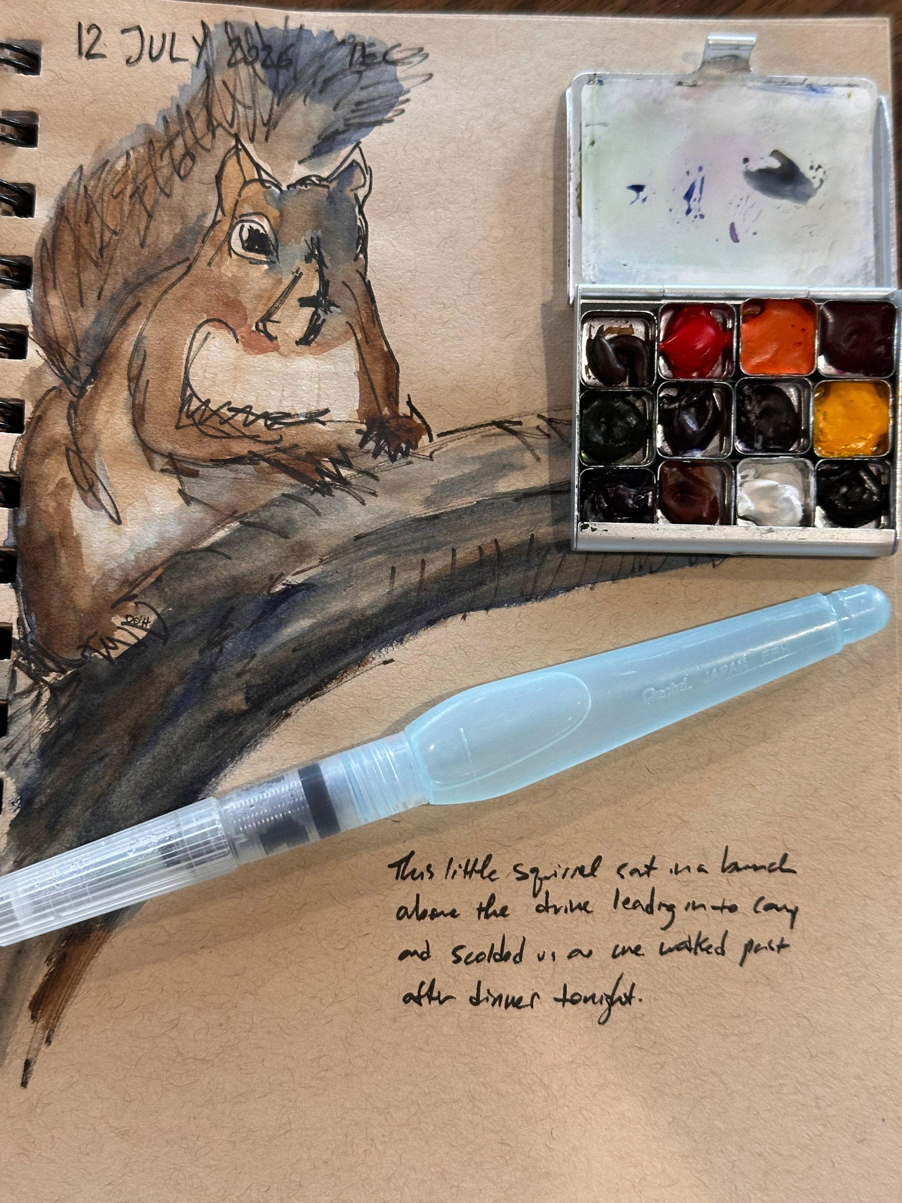 A watercolor painting of a squirrel on a branch is accompanied by a small paint palette, a water brush, and handwritten notes on the paper.