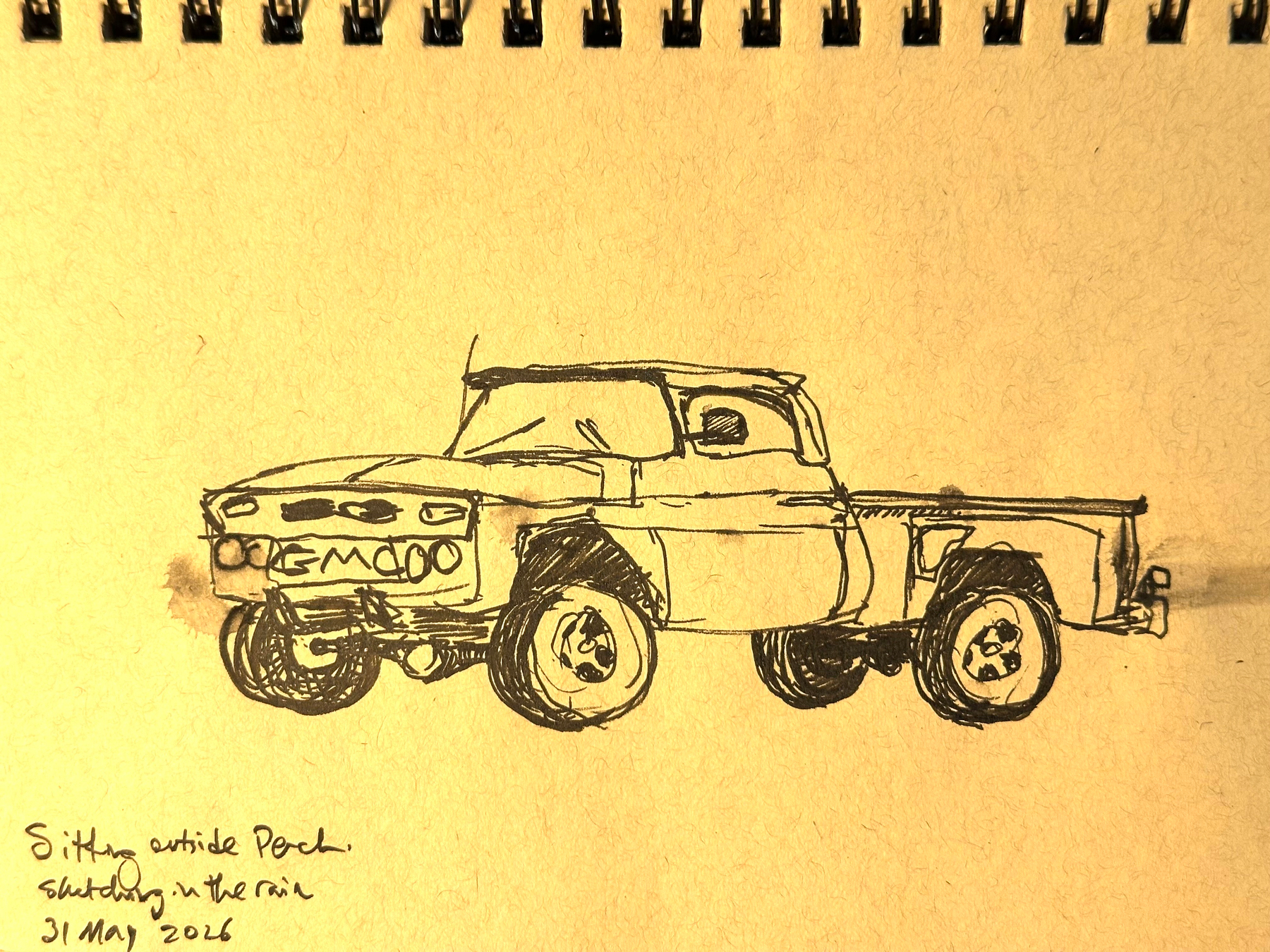 A sketch on a notebook page depicts a classic pickup truck, accompanied by handwritten notes about sitting outside and drawing in the rain on May 31, 2006.