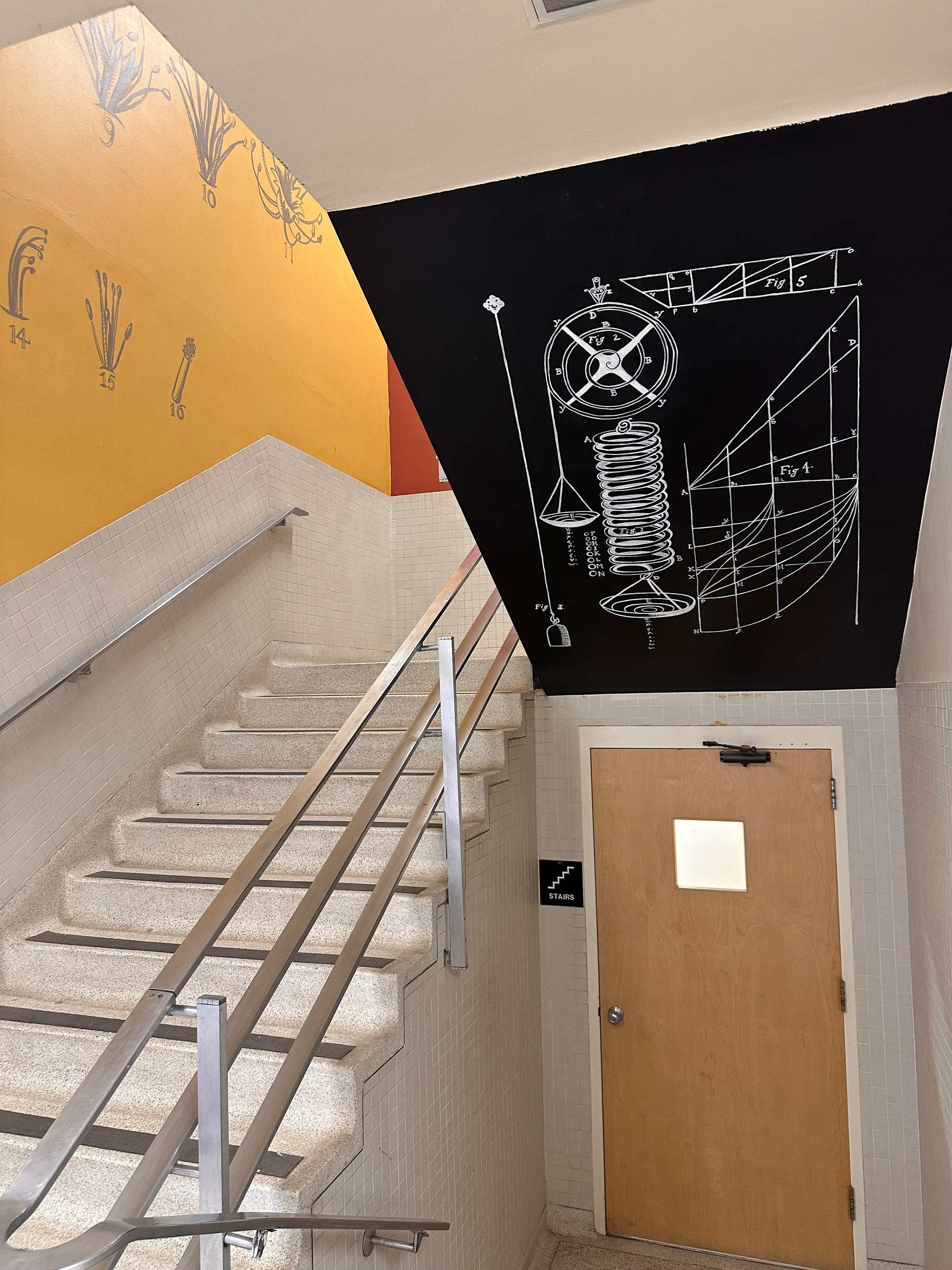 A staircase with a wall displaying scientific diagrams and illustrations.